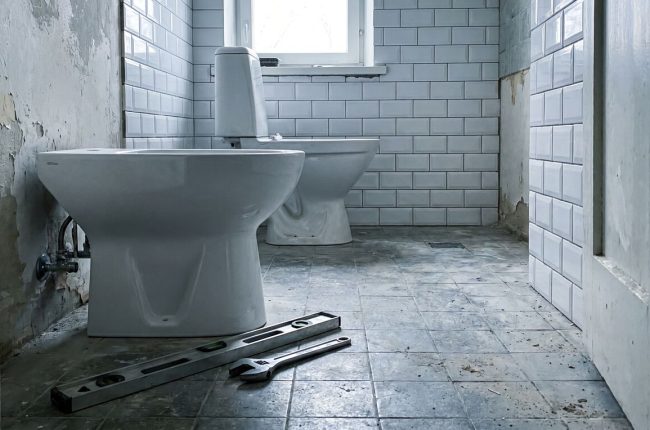 Установка биде в Таллинне — новый белый биде рядом с унитазом, инструменты на полу